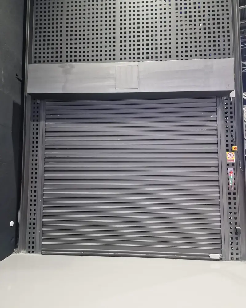Puerta enrollable cerrada en el acceso a la plataforma de un elevador de vehículos