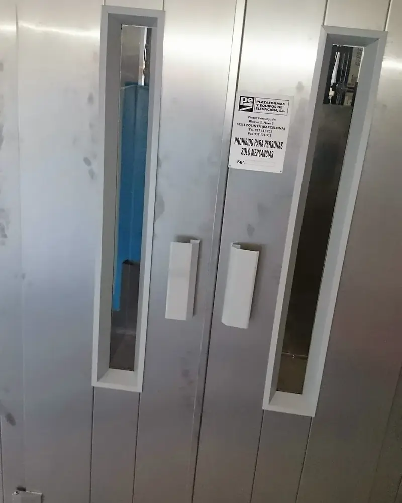 Puertas de un equipo de elevaci&oacute;n de mercanc&iacute;as instalado en un paramento, con la placa de caracter&iacute;sticas de la empresa