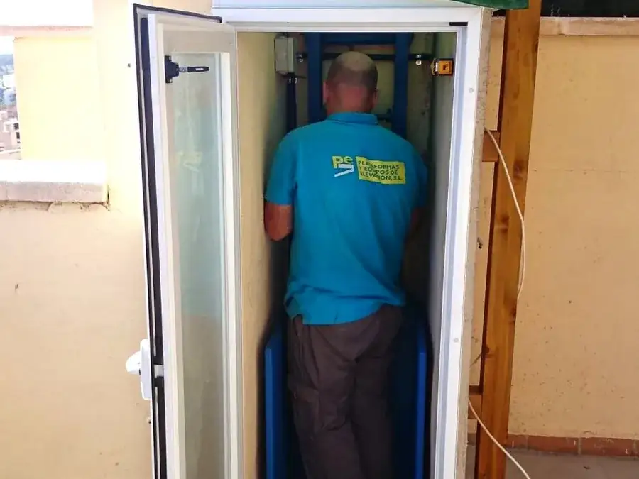 Técnico de Plataformas y Elevación dentro de la cabina de una plataforma elevadora instalada en una terraza