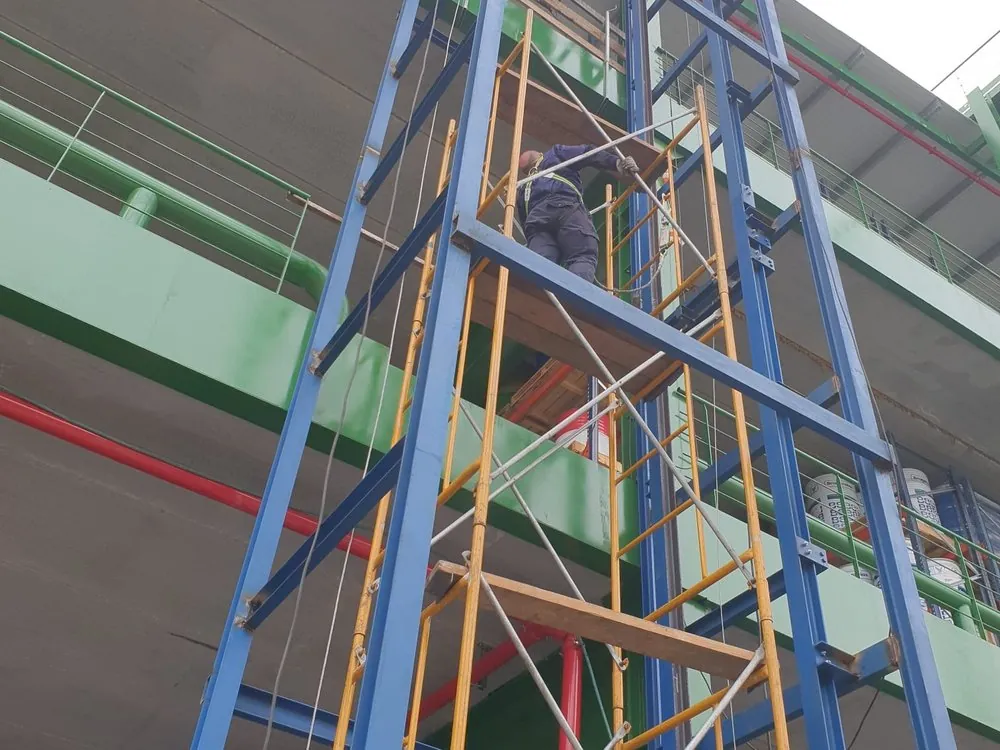 Operario trabajando en altura sobre la estructura de un elevador