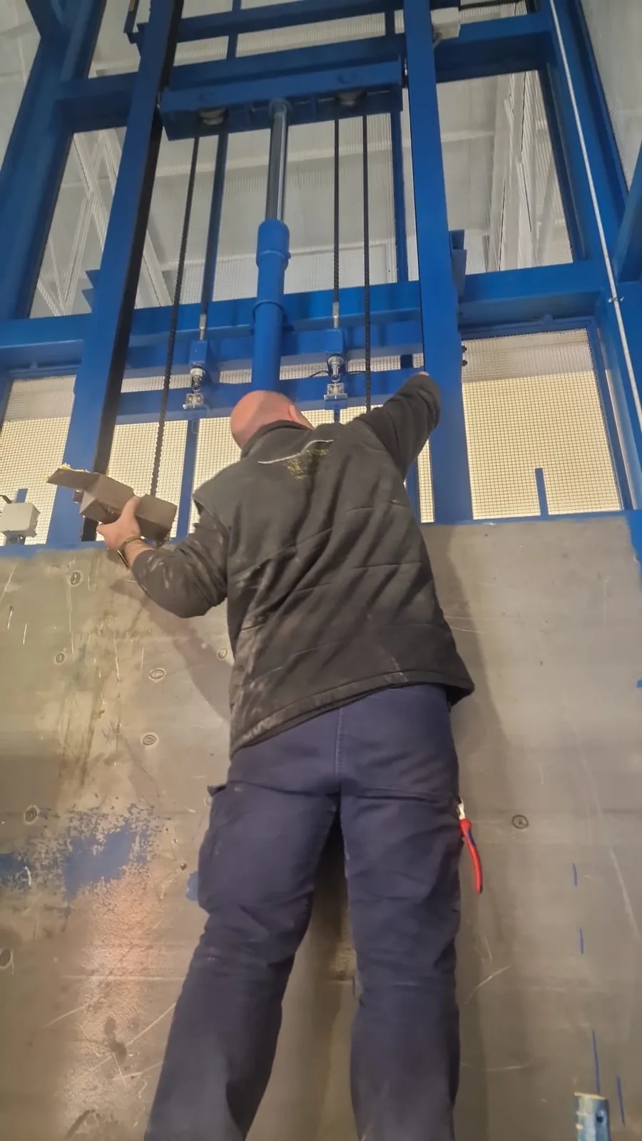 Técnico de Plataformas y Elevación instalando un montacargas en obra