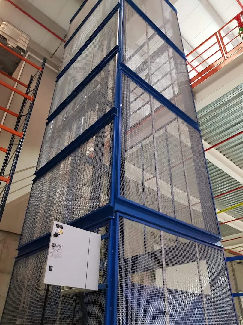 Montacargas de malla azul de gran altura instalado en un almacén
