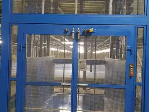 Puertas de dos hojas de un montacargas de malla azul con su cerradura y el cartel de carga