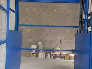 Plataforma de un montacargas a nivel de suelo, abierta a un local con pared de bloques
