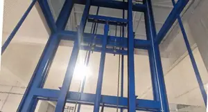 Interior del hueco de un montacargas visto desde abajo, con el cilindro y la estructura azul