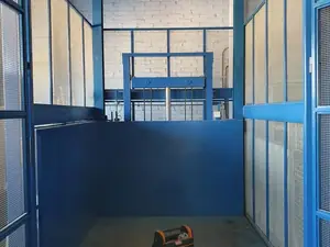 Plataforma de un montacargas con sus puertas de malla en un local de paredes blancas