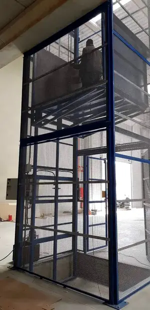 Montacargas de malla azul de gran altura con un operario en la plataforma superior